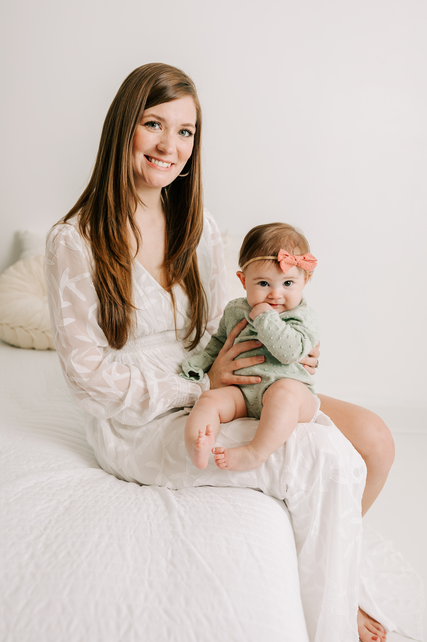 Mom and daughter sharing a smile on the bed in the studio of molly berry photography. mom is using one of the lactation consultant Atlanta GA for her breastfeeding questions.
