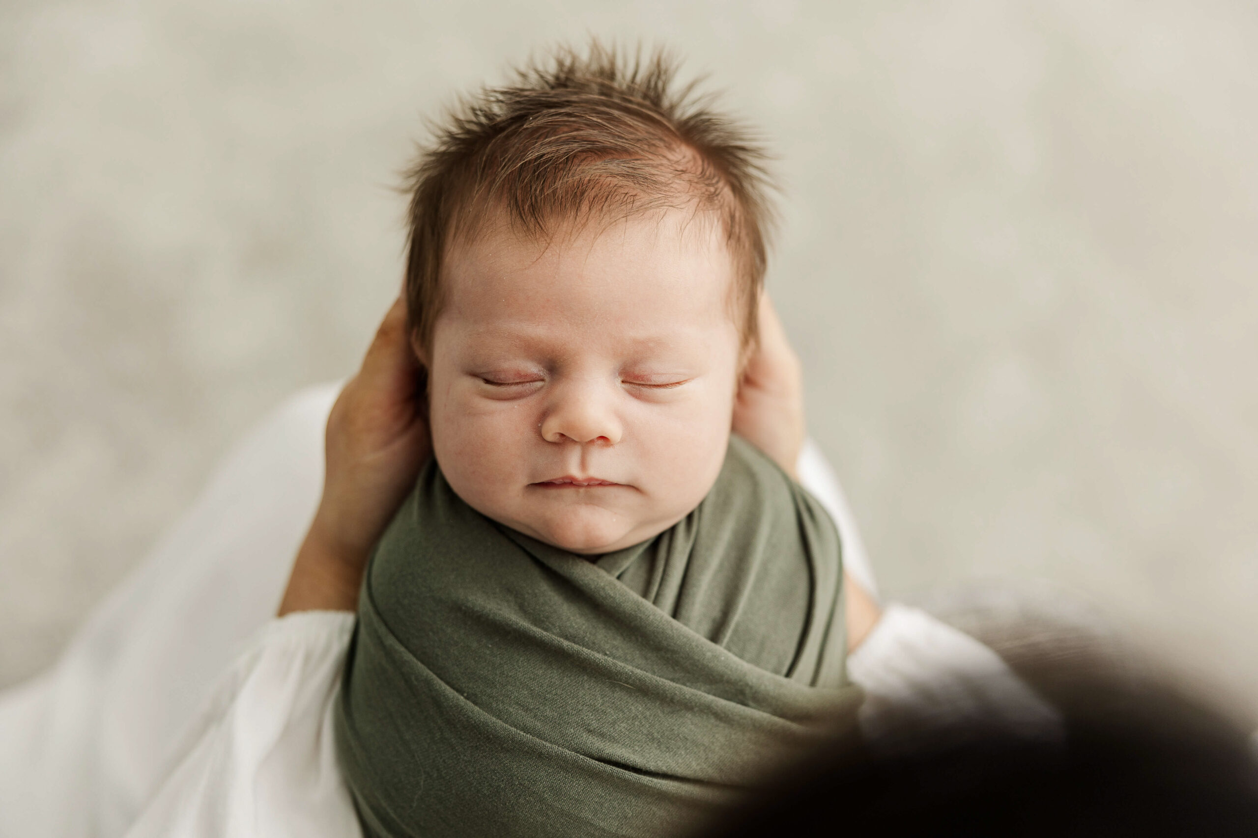 Newborn baby wrapped in a green swaddle.