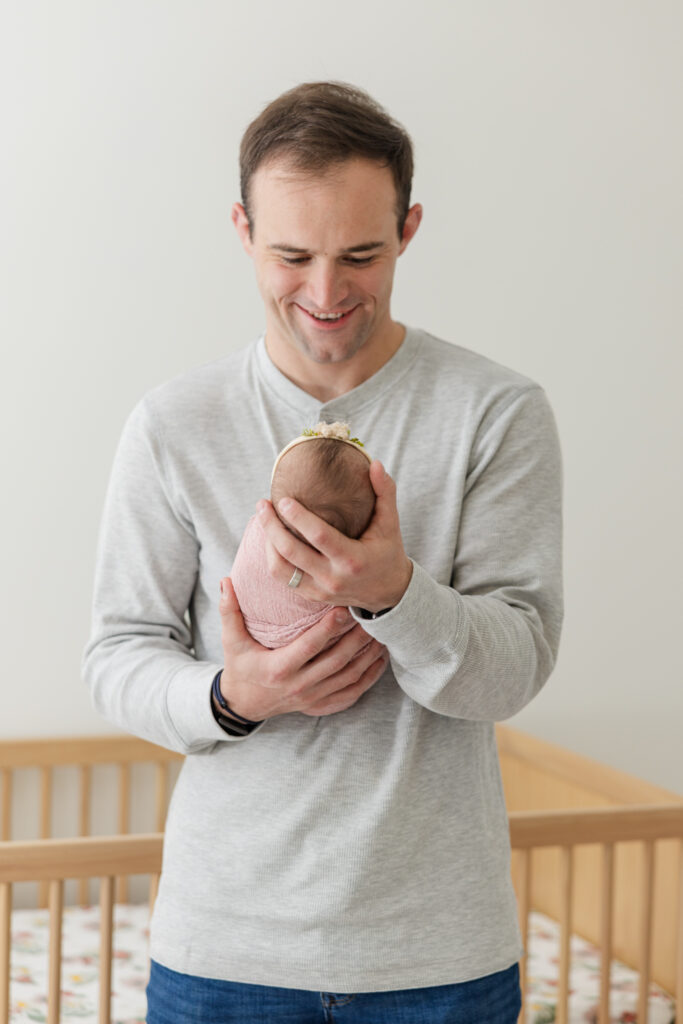 Newborn in home session with Molly berry photographer. Dad is holding a baby