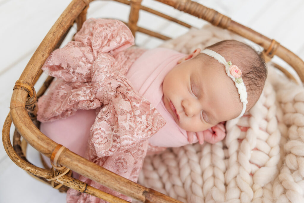 In home newborn portrait of a baby in a basket, swaddled in pink