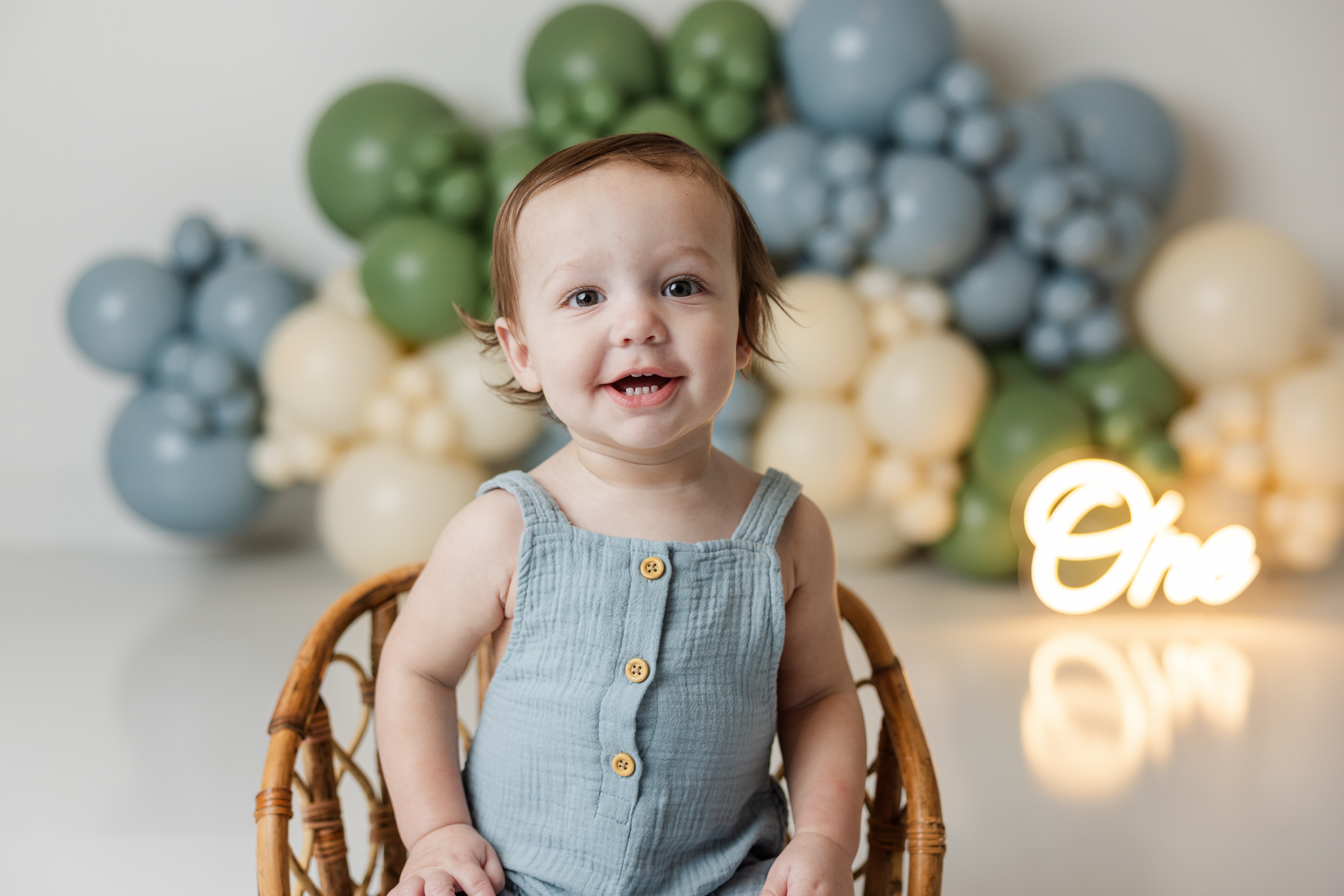 one year old boy wearing a blue romper in the studio of molly berry photography for his one year old cake smash session